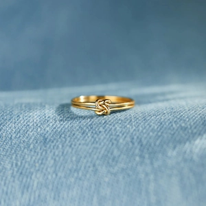 Macro view of double-layer knotted gold ring on a textured denim background