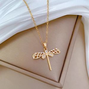 Elegant gold hollow dragonfly necklace with sparkling crystals on white satin background
