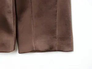 Macro view of brown satin blazer sleeve detailing with smooth glossy finish and premium stitching