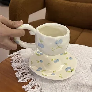 Detail of hand-painted blue floral patterns on a wavy edge ceramic coffee cup and saucer