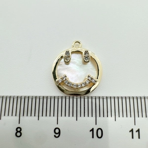 Detailed view of 18K gold plated smiling face pendant with mop inlay and rhinestones