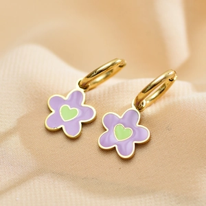 Close-up of golden hoop earrings with purple flower charms and green heart centers