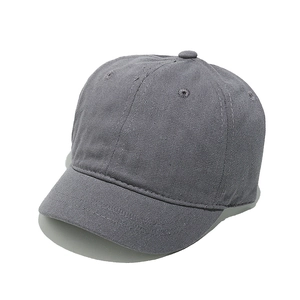 Detail of dark grey short brim baseball cap showing washed cotton texture and stitching