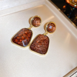 Close-up of vintage amber resin earrings with gold leaf textures in a jewelry box
