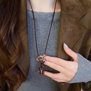 Detail view of long sweater necklace featuring a dark red bear pendant and beaded cord