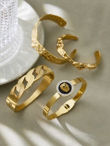 Detailed macro view of four 18k gold-plated hammered bracelets with lion head medallion