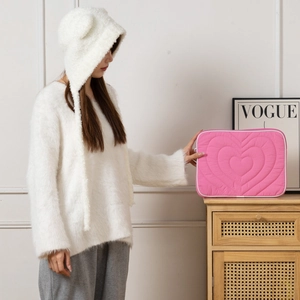 Detail of pink quilted laptop sleeve with heart patterns and white stitched edges