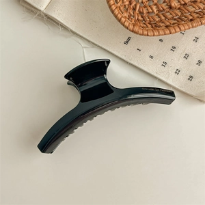 Detailed macro view of black leopard hair claw clip on beige surface with rustic background
