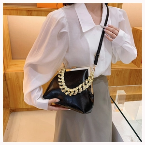 Detail of black pebbled leather handbag with chunky gold chain and vintage metal clasp