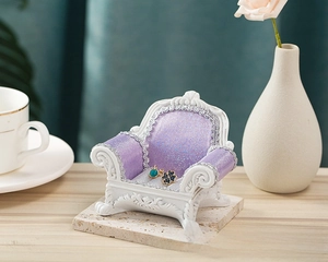 Miniature vintage sofa jewelry stand with purple glitter fabric and white base for display
