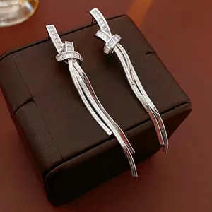 Silver knot tassel earrings with sparkling cubic zirconia on a luxury leather surface
