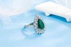 Close-up of a pear-cut emerald ring with micro-pave zircons on a silver band