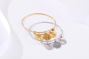 Detail view of gold and silver adjustable bangles with love charms and hollow figures