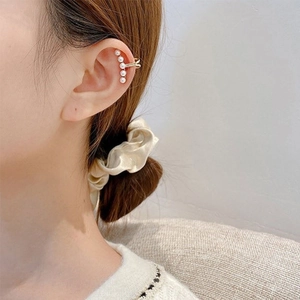 Close-up of elegant gold pearl ear cuff worn on ear, minimalist clip-on earring design