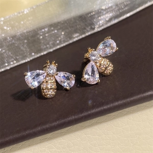 Macro shot of bee earrings with zircons and gold plating on a textured base