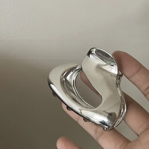 Macro detail of silver heart-shaped cutout metal hair claw clip with mirror finish