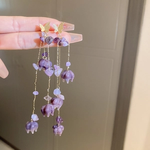 Detail of purple flower drop earrings with golden butterfly and dangling crystals