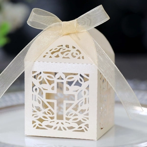 Macro shot of white laser-cut wedding favor box with cross pattern and ribbon bow