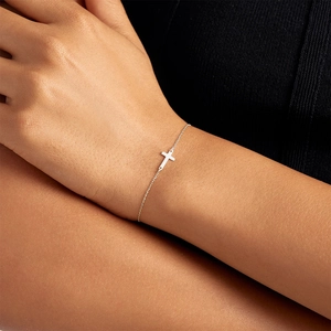 Macro view of dainty S925 sterling silver cross bracelet on wrist with fine chain detail