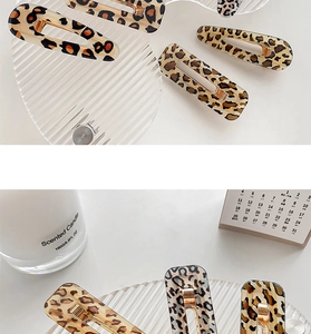 Detail of leopard print acetate hair clips set on glass tray with candle décor