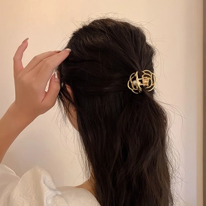 Detail of elegant gold metal hair claw clip with pearl on model's brunette hair