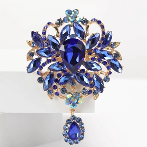 Vue détaillée d'une broche dorée de luxe avec cristaux bleu foncé et élégant pendentif en goutte