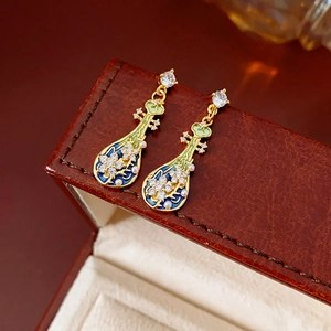 Dettaglio macro di orecchini vintage con smalto blu, perle e zirconi brillanti