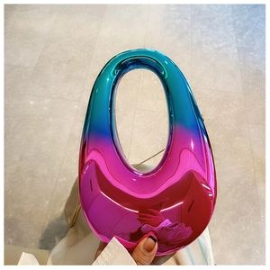 Close-up of gradient acrylic oval clutch with gold chain strap for party and evening events