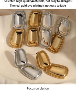 Detail of gold and silver rectangle drop earrings on ceramic tray showing PVD plating quality