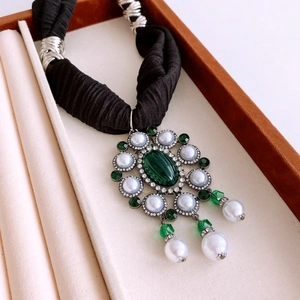 Detailed macro view of vintage emerald green pendant with pearls and tassels on necklace