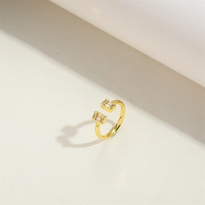 Close-up of golden adjustable ring with square zircon stones on a beige surface
