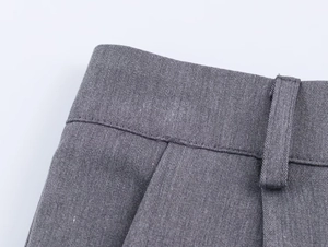 Vue détaillée du tissu en sergé gris et des coutures de haute qualité sur le pantalon