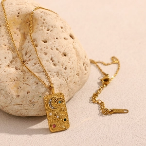 Close-up of gold star and moon rectangular pendant with inlaid colorful gemstones