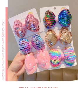 Close-up of children's sequin bow hair clips in multiple colors on a display card