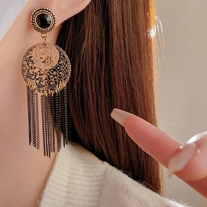 Detail of vintage bronze coin earrings with metal tassels shown on a female model