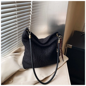 Detailed view of black tweed shoulder bag with leather strap and golden hardware