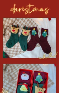 Detail of plush Christmas socks with 3D reindeer and Santa dolls in a holiday gift box