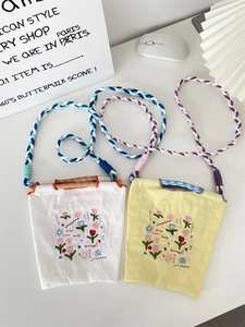 Détail des mini sacs bandoulière en tissu Oxford brodé avec cordons colorés en blanc et jaune