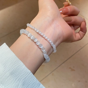 Close-up of layered white cat-eye bead bracelets in 4mm and 6mm sizes on a wrist