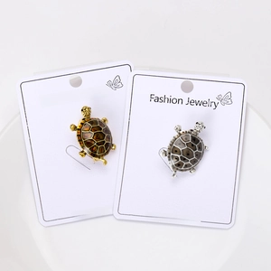 Detailed view of turtle brooches with amber and grey enamel shells on display cards