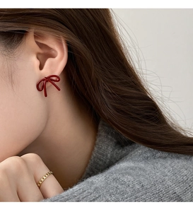 Detailed view of deep red lacquer bow stud earring with a golden chain link ring