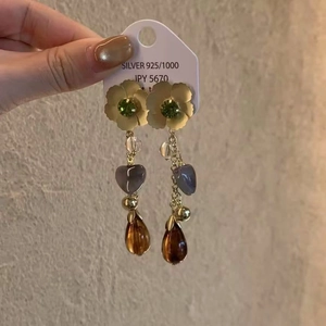 Vue détaillée des boucles d'oreilles à pompons, perles en cœur et pendentif en résine ambre