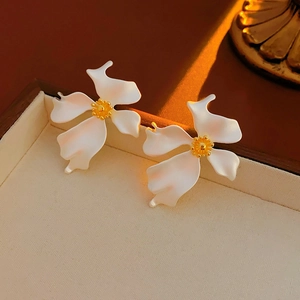 Detailed close-up of vintage matte flower earrings with white petals and gold pistils