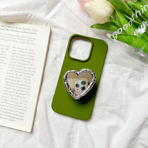 Green silicone phone case with silver heart mirror grip stand on white textured fabric