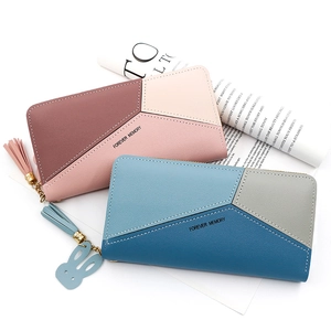 Detail of zip-around wallet with patchwork design, fringe tassel, and rabbit charm