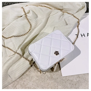 Detail view of a white quilted PVC jelly bag with flower clasp and gold chain strap