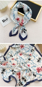 Detail of silk scarf with blue vines and pink flowers, featuring navy blue hemmed edges