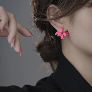 Detailed close-up of pink flower petal earrings with gold trim worn by a model