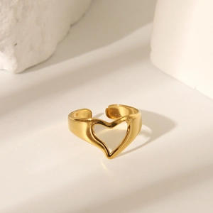 Détail d'une bague ouverte en forme de cœur évidé dorée sur une base en pierre texturée