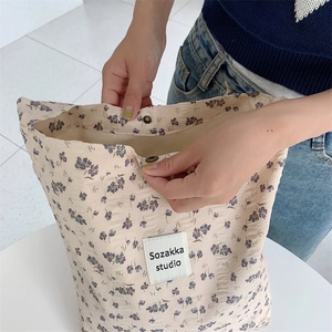 Close-up of floral tote bag with purple flower pattern and metal snap button closure